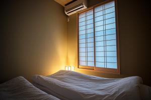 um quarto com uma cama e uma janela em Bungetsu Shokaku Kaikan em Quioto