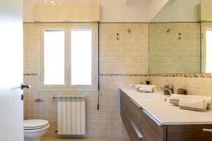 bagno con lavandino, servizi igienici e finestra di La Dimora Dei Ciclopi ad Aci Castello