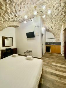 um quarto com uma grande cama branca e uma televisão em Petrakis Inn em Jerusalém
