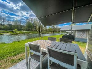 a wooden table and chairs with a view of a river at Country Camp camping Echternacherbrück in Echternacherbrück