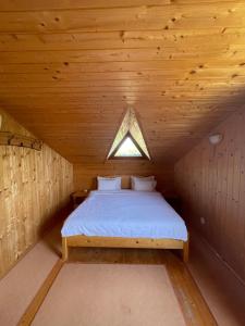 Cama en habitación de madera con ventana en Pensiunea Pagaya, en Gorgova