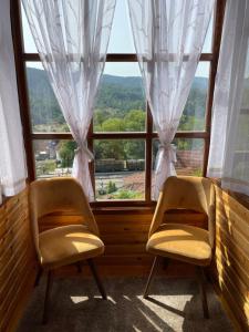 zwei Stühle vor einem Fenster in der Unterkunft Konačište Osmica in Mokra Gora