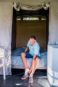 a man sitting on a bed in a tent at Country Camp camping Echternacherbrück in Echternacherbrück