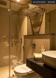 a bathroom with a toilet and a sink and a shower at BayLeaf Inn in Port Blair