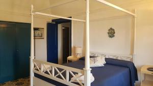 a bedroom with a canopy bed with a blue blanket at La Villa Rossa in Santa Marina Salina