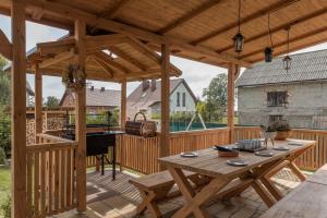 a wooden pergola with a wooden table on a deck at Cyprysovnia in Gnieżdżewo