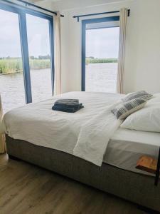 a bedroom with a large bed with a view of the water at Surla luxury sailing Houseboat Splendid at Marina Monnickendam in Monnickendam