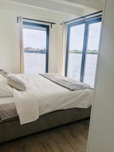 een slaapkamer met een groot bed en een groot raam bij Surla luxury sailing Houseboat Splendid at Marina Monnickendam in Monnickendam