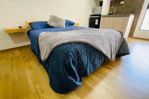 um quarto com uma cama com um cobertor azul e piso em madeira em Hermoso y cómodo monoambiente em Cochabamba