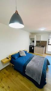 um quarto com uma cama azul e uma cozinha em Hermoso y cómodo monoambiente em Cochabamba