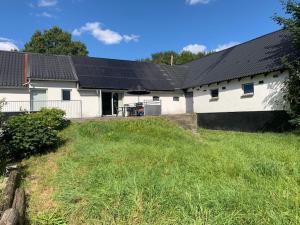 una casa blanca con paneles solares. en Medomgaard, en Kibæk