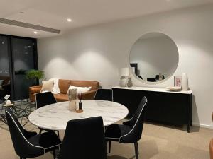 een woonkamer met een tafel en een spiegel bij Modern 3 Bedroom 2 Bathroom Apt Southbank in Melbourne