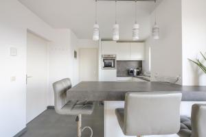 cocina con armarios blancos, mesa y sillas en Nice studio with big terrace en Bruselas