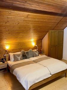 ein großes Bett in einem Schlafzimmer mit einer Holzwand in der Unterkunft Wildbach Chalet Turrach in Turracher Hohe