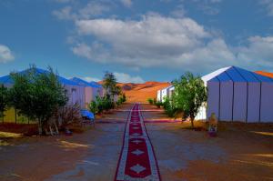 a street with a row of buildings and trees at Les Roches Desert Camp in Merzouga