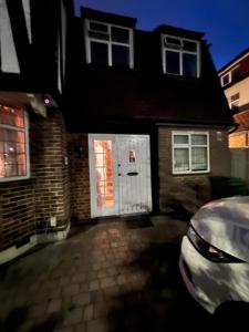 a brick house with a white door and a car at Barnet Serviced Accommodation - Elegant 5-Bedroom Home, Just a 7-Minute Stroll from High Barnet Station - Book Your Stay Today!" in New Barnet