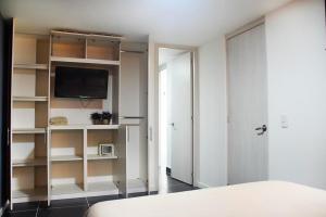a bedroom with a bed and a tv and shelves at Espectacular Apt de 3 habitaciones Deluxe! in Envigado