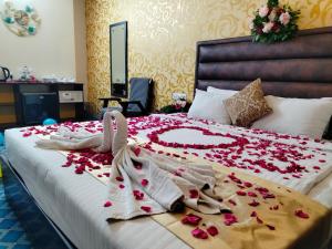 a bed with white towels and red flowers on it at Grand Mostafa Hotel in Sylhet +62 photos