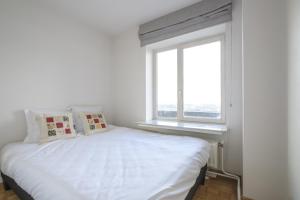 a white bed in a room with a window at Nice studio with big terrace in Brussels