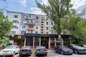 una calle de la ciudad con coches aparcados frente a un edificio en Яркая Квартира на Арбате en Almaty