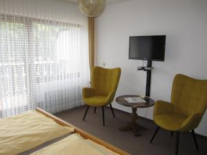 a bedroom with two chairs and a bed and a tv at Pension-Gästehaus Waldhof in Winterberg