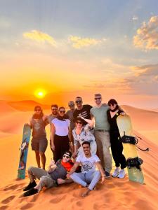 a group of people standing in the desert with snowboards at Les Roches Desert Camp in Merzouga