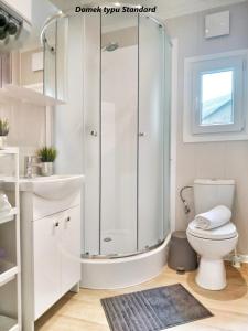 uma casa de banho branca com um chuveiro e um WC. em LUXURY CAMP - 150 m od Suntago Park em Grabce
