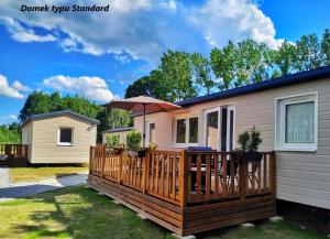a house with a wooden deck with an umbrella at LUXURY CAMP - 150 m od Suntago Park in Grabce-Towarzystwo