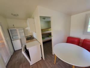 a small room with a white table and a white refrigerator at kamp katra mobilna hiška EXCLUSIVE in Vinica