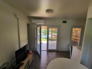 a living room with a television and a sliding glass door at kamp katra mobilna hiška EXCLUSIVE in Vinica