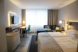 um quarto de hotel com uma cama e um sofá em Holiday Inn Düsseldorf-Neuss, an IHG Hotel em Neuss