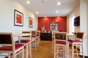 a restaurant with tables and chairs and a red wall at Red Roof Inn & Suites Beaumont in Beaumont
