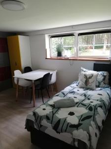 een slaapkamer met een bed en een tafel en ramen bij Les studios du Domaine d'Eva in Libramont