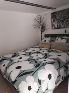 a bedroom with a bed with a black and white comforter at Les studios du Domaine d'Eva in Libramont