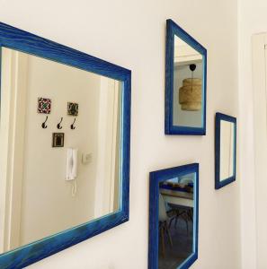 un espejo azul colgado en una pared con cuadros enmarcados en Donna Leda - Guest House, en Castro di Lecce