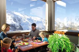レ・メニュアールにあるBelambra Clubs Les Menuires - Neige Et Cielの山の景色を望むレストランで家族が食事をする