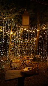 una cadena de luces colgando de un árbol con una mesa en Ô Pays Des Bois - Hébergements insolites en pleine nature, en Parmilieu