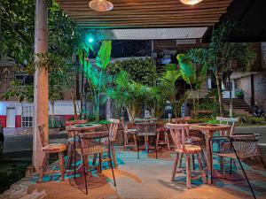 an outdoor restaurant with tables and chairs and trees at Urban Hostal Bar in Bucaramanga