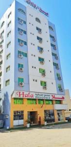 un edificio blanco alto con un letrero. en HALA HOTELS APARTMENTS, en Sharjah