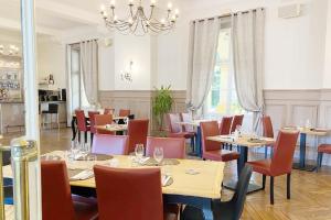 un ristorante con tavoli, sedie e un lampadario di PROXIMITE LE PAL- Appartement 4 pers - Entrée SPA incluse a Bourbon-Lancy