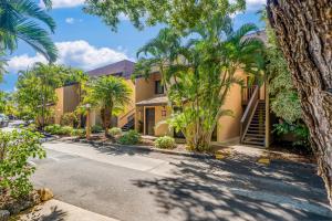 a street in front of a building with palm trees at Kihei Gardens Estates G104 in Kihei