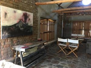 ein Zimmer mit einem Tisch und Stühlen sowie einem Gemälde an der Wand in der Unterkunft Die Kapokbosskuur in Nieu-Bethesda