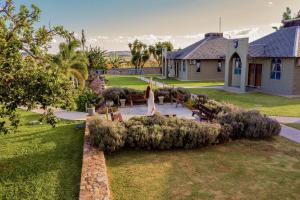 a woman walking through a garden in front of a house at Pousada Camelot Inn in Alto Paraíso de Goiás