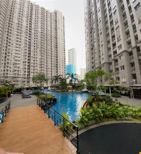 a pool in the middle of a city with tall buildings at Super Cozy 2BR Apt with direct access to Mall in Jakarta