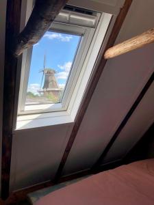 una ventana en una habitación con un molino de viento en Tiny House De Smederij en Peize