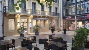 una strada vuota con tavoli e sedie di fronte agli edifici di SQUARE HOTEL a Nîmes