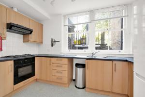 a kitchen with wooden cabinets and a sink and a window at Bedford Place Hostels in London
