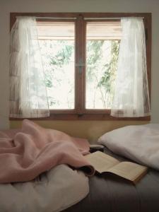 a book laying on a bed with a window at Roztomilá a utulná chata Azzy na samotě v lese. in Valašské Klobouky