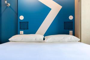 una cama con una letra k en una pared azul en ibis Budget La Rochelle Centre, en La Rochelle