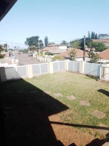 a large backyard with a white fence and grass at Rato Thato Guest House in Durban